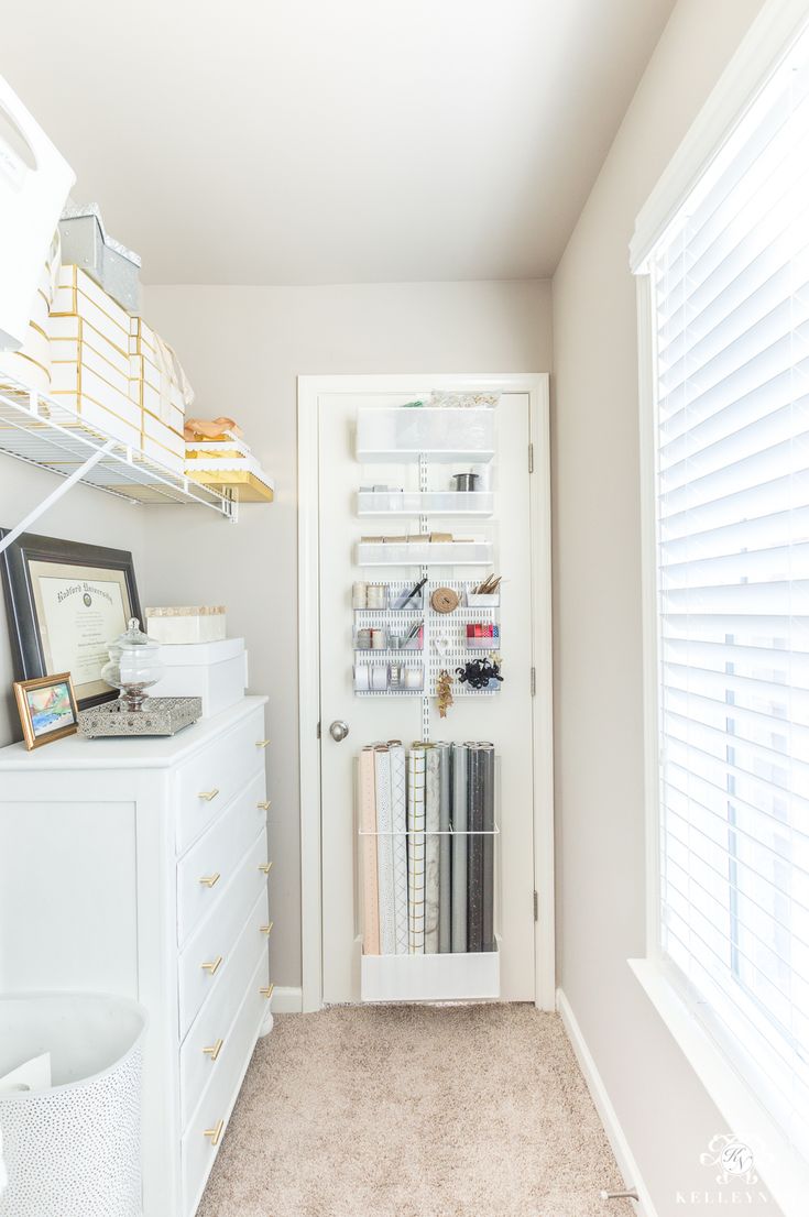 a white closet filled with lots of books next to a window covered in blinds and shutters