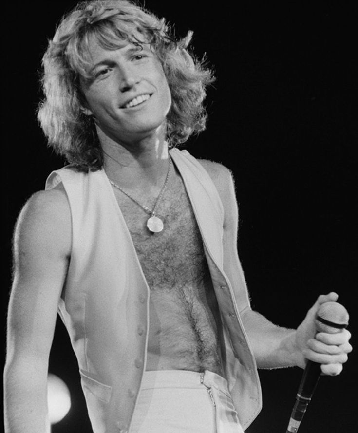 a black and white photo of a shirtless man holding a tennis racquet