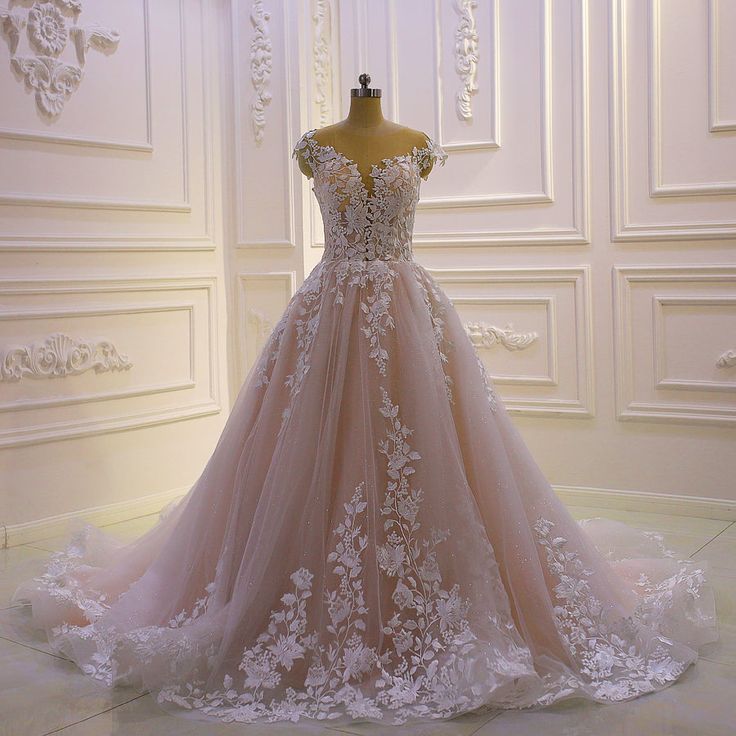 a wedding dress is displayed on a mannequin in front of a white wall