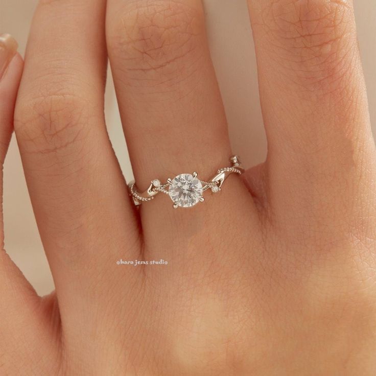 a woman's hand with a diamond ring on top of her finger and an engagement band