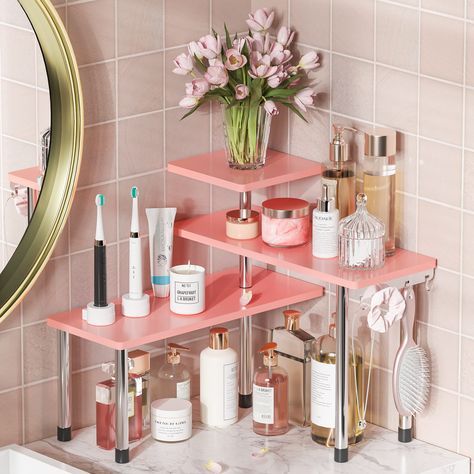 a bathroom with pink shelving and flowers on the counter top, in front of a mirror