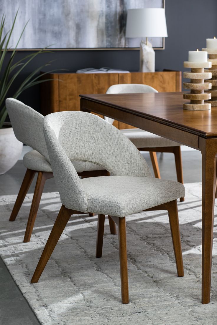 a dining room table with chairs and a rug on the floor in front of it