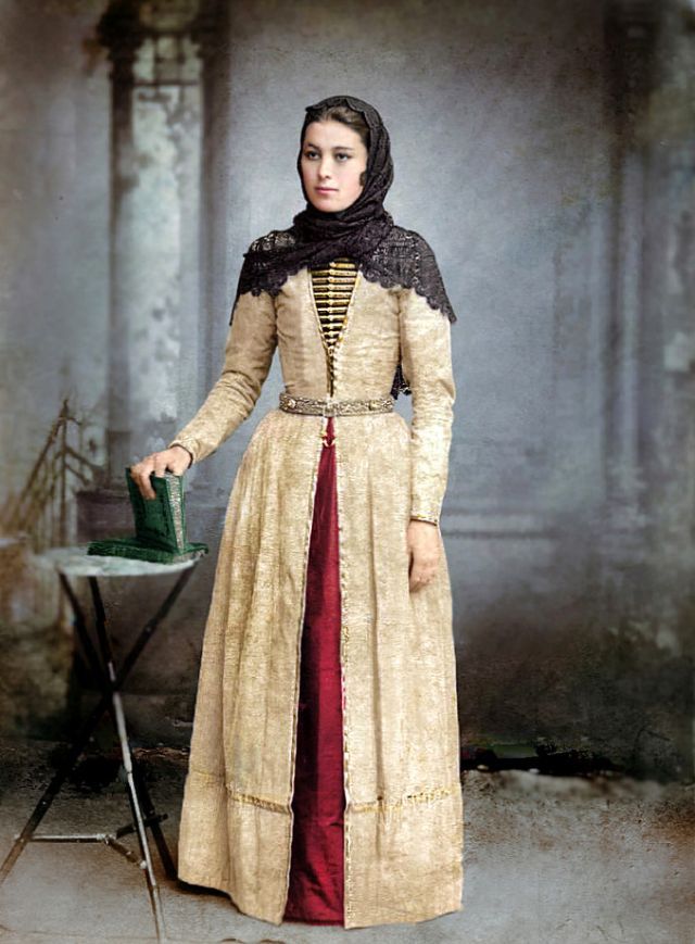 an old fashion photo of a woman in period dress holding a watering can and standing next to a ironing board