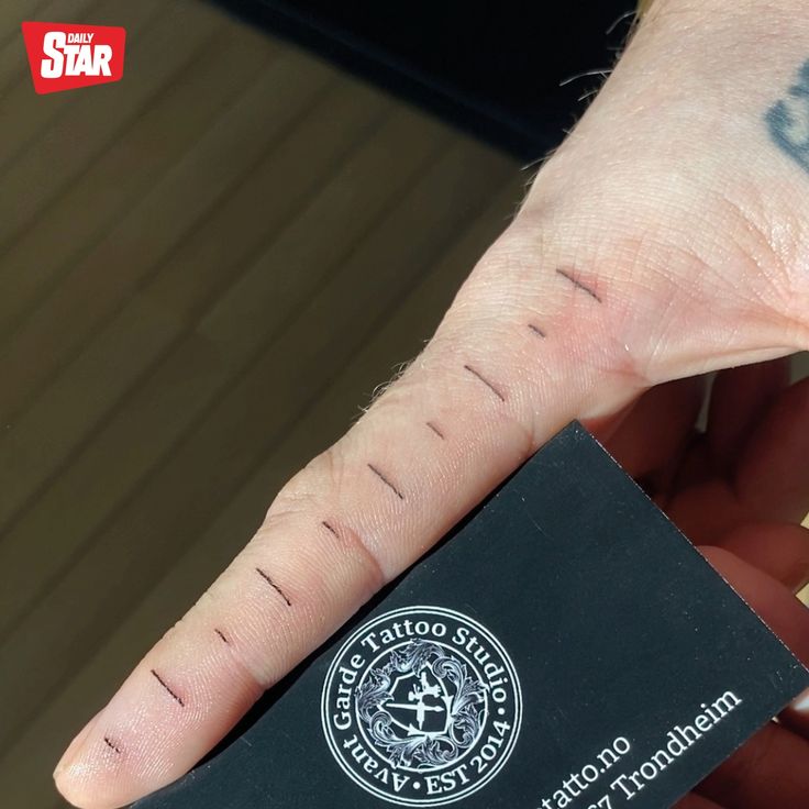 a person's hand with a tattoo on it holding a small black business card