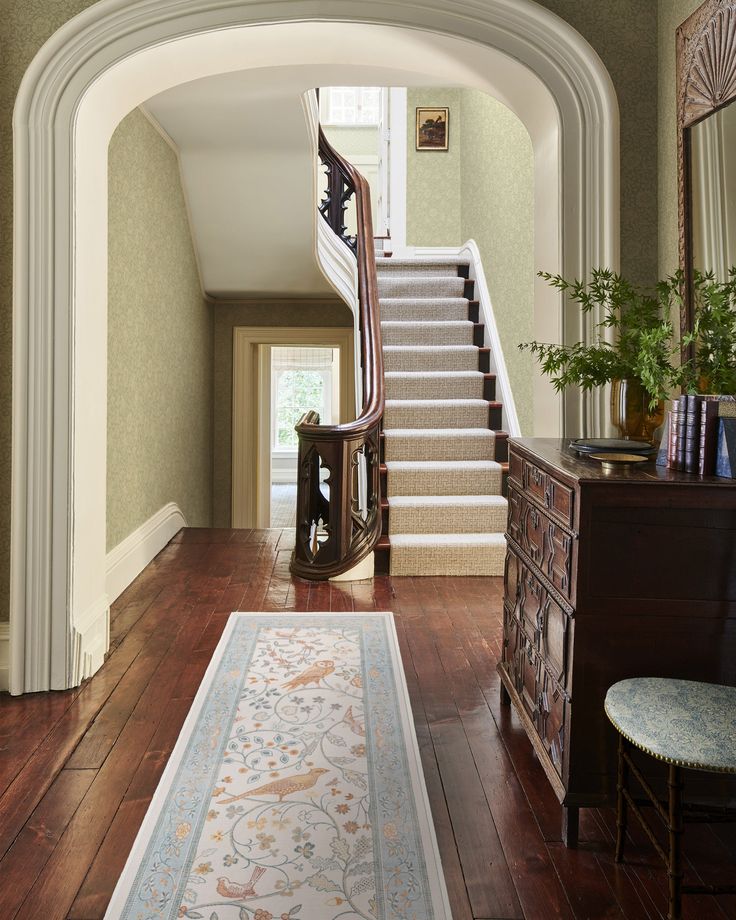 an archway leads to the second floor, and is flanked by a stair case with a rug on it