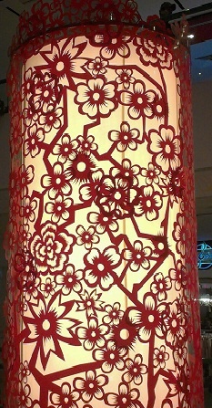 a red lamp that is lit up in the dark with flowers and leaves on it