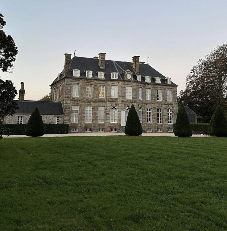 a large building with lots of windows on top of it's roof and green grass in front of it