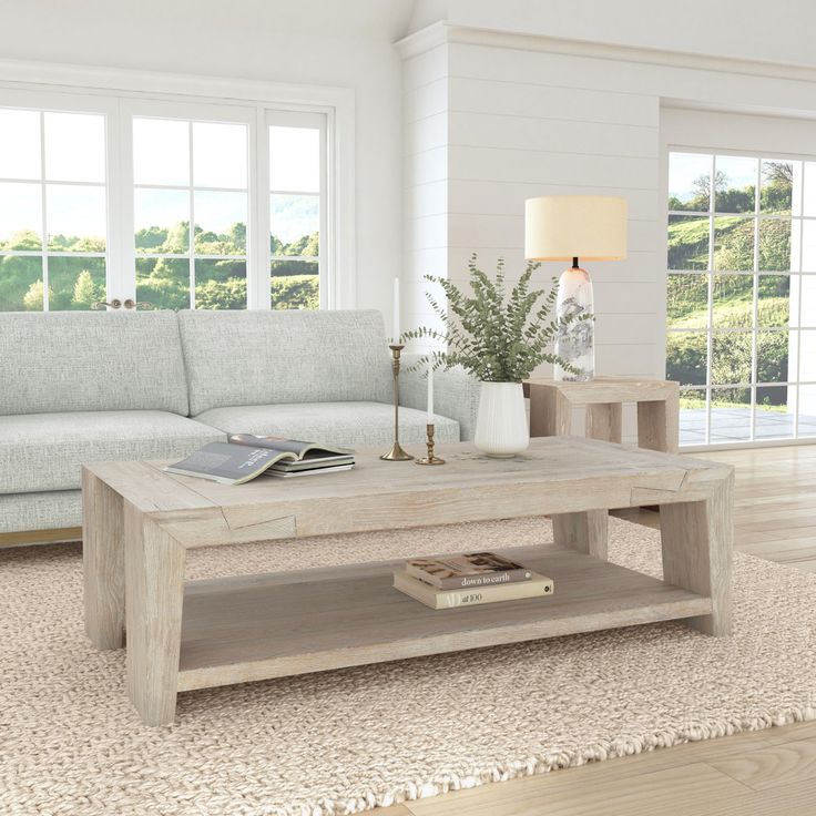 a living room with a couch, coffee table and two end tables in front of windows