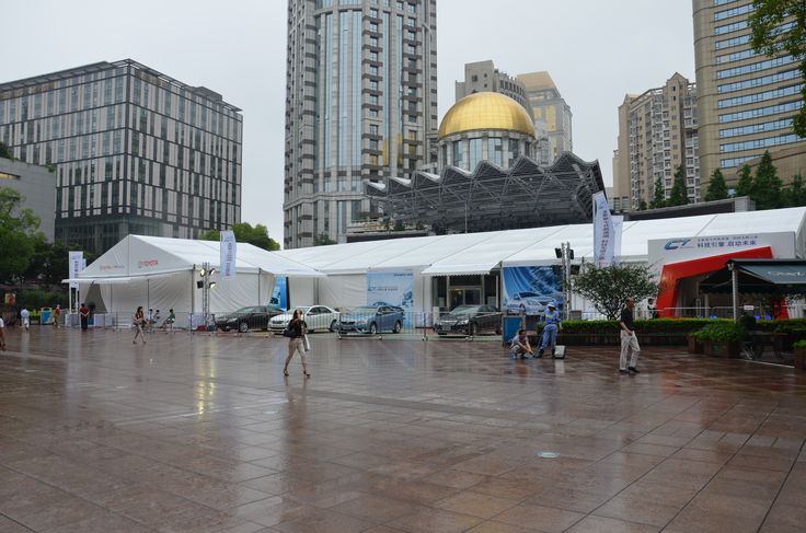 people are walking around in the rain near some tall buildings and large tents with gold domes on them