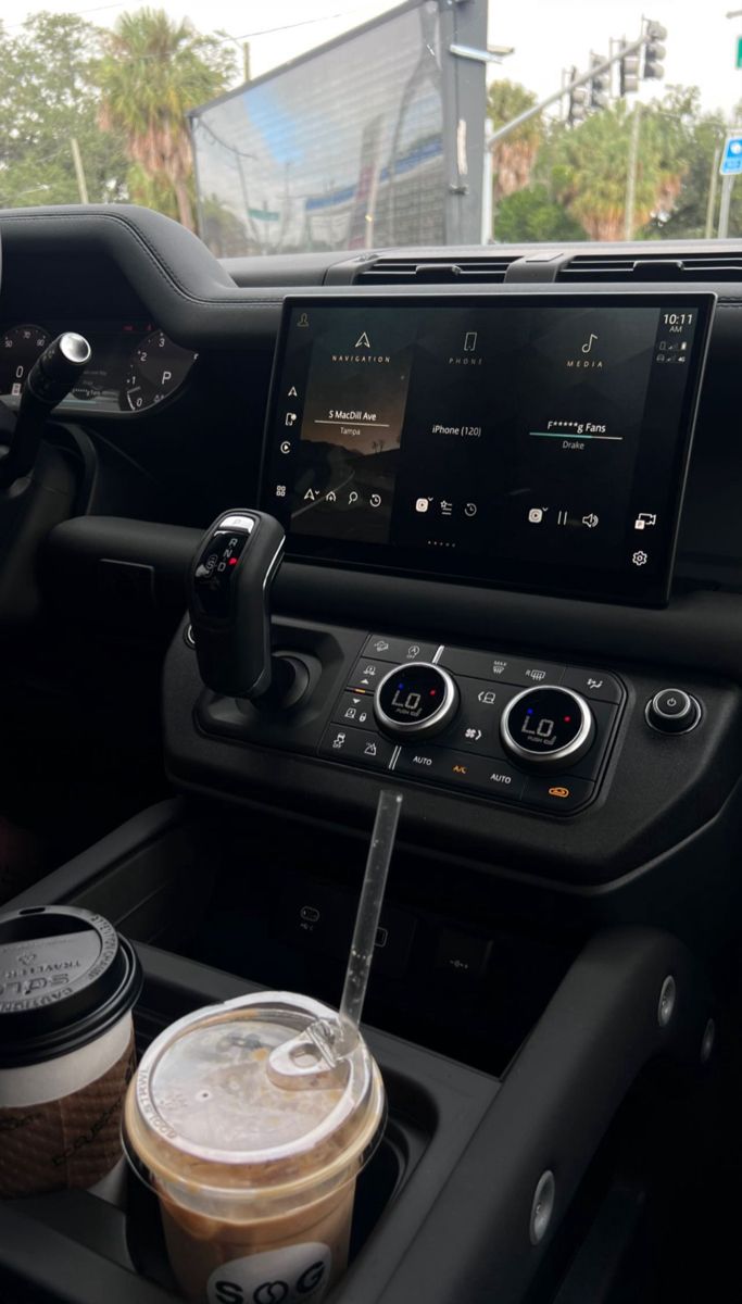 the interior of a car with coffee and an appliance on it's dashboard