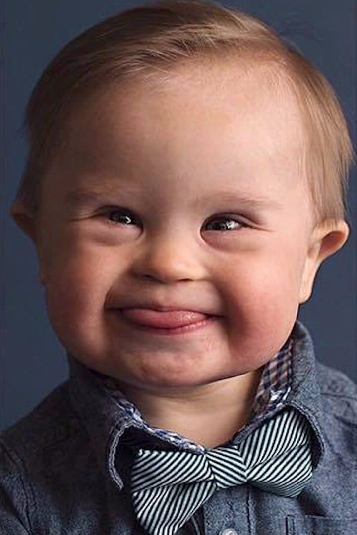 a smiling baby wearing a blue shirt and bow tie