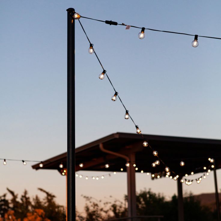 the lights are hanging from the pole in front of the gazebo at night time