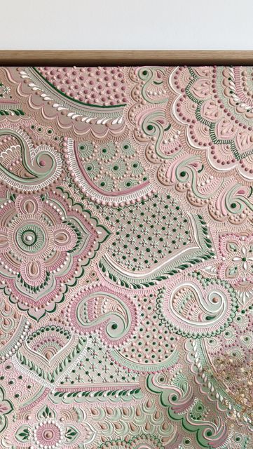 a pink and green paisley wall hanging on a white wall