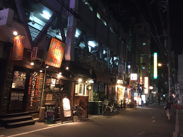 an empty street at night with people walking on the sidewalk