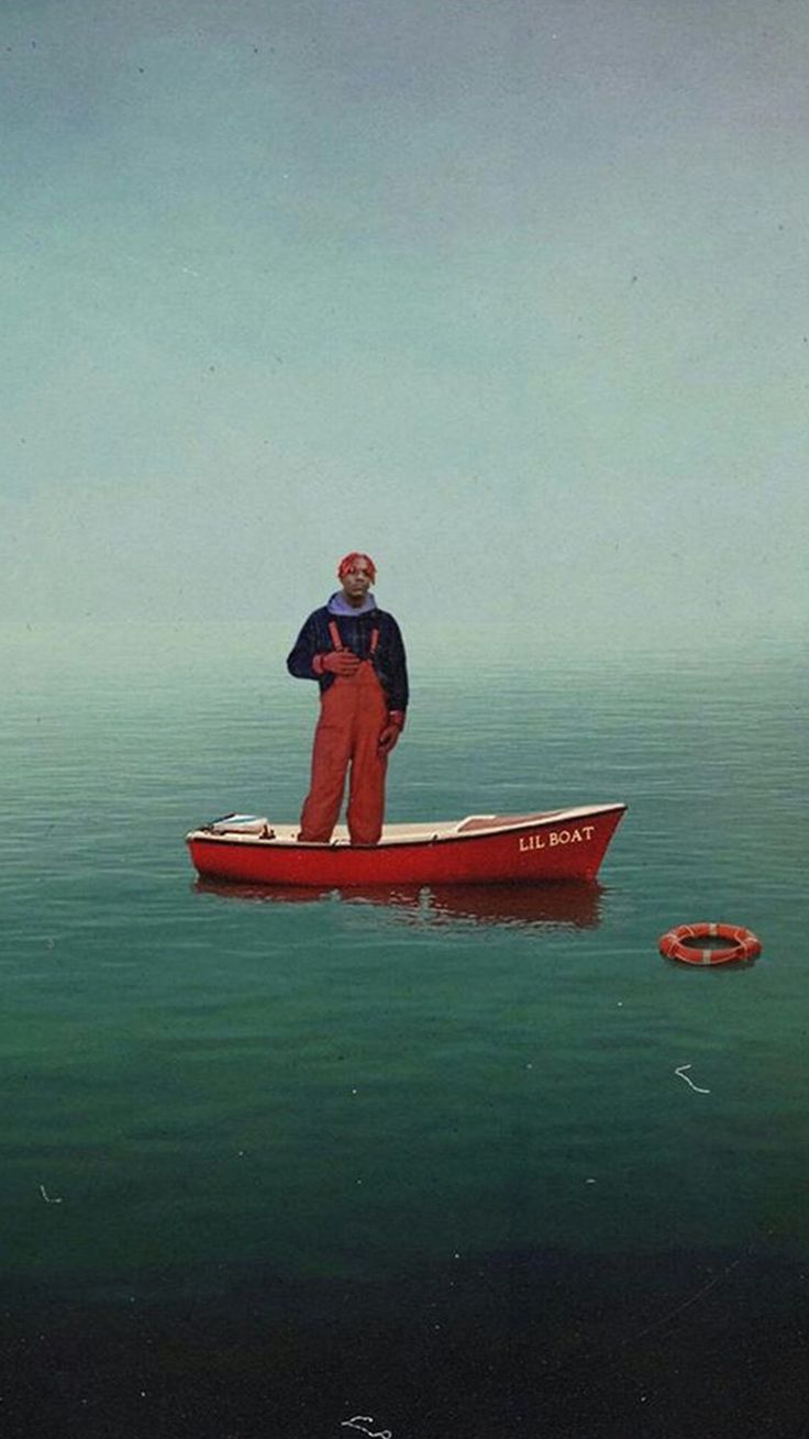 a man standing on top of a red boat in the water