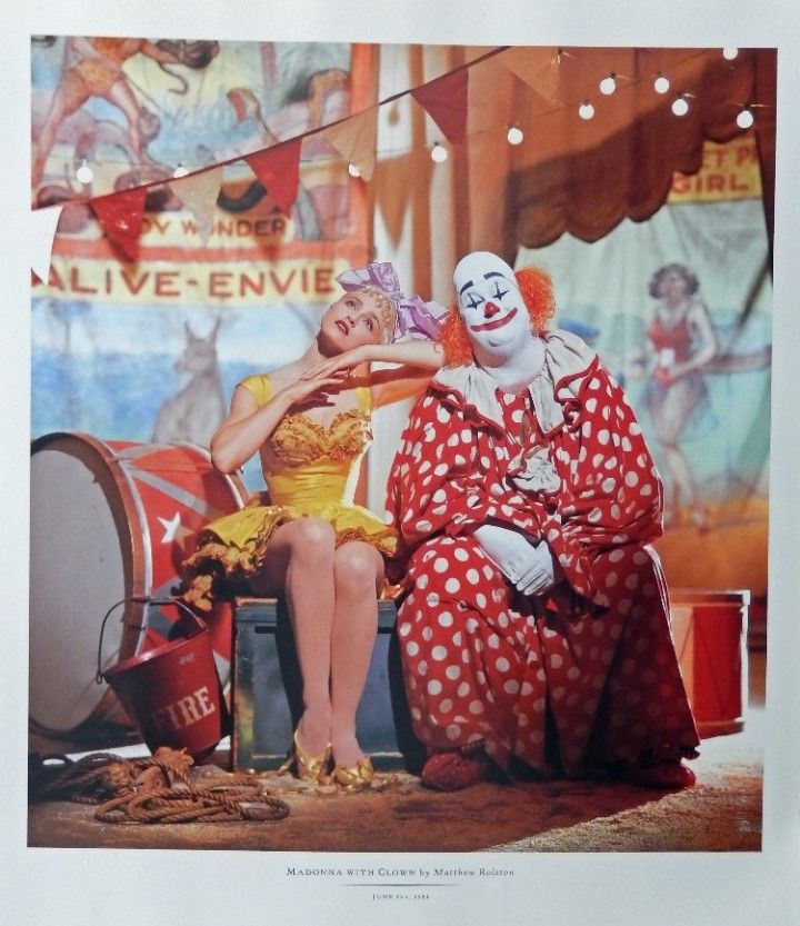 two clowns are sitting next to each other in front of a circus sign and drum