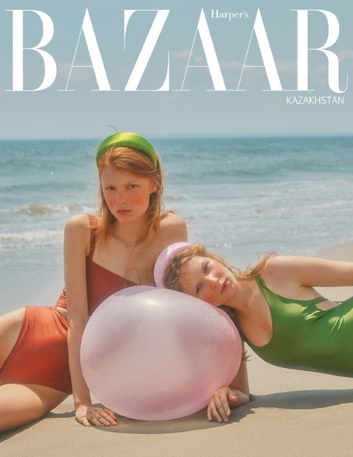 two young women laying on the beach with a large balloon in front of their face