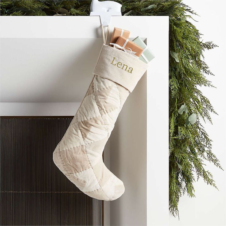 a christmas stocking hanging from the side of a fireplace with evergreen branches around it