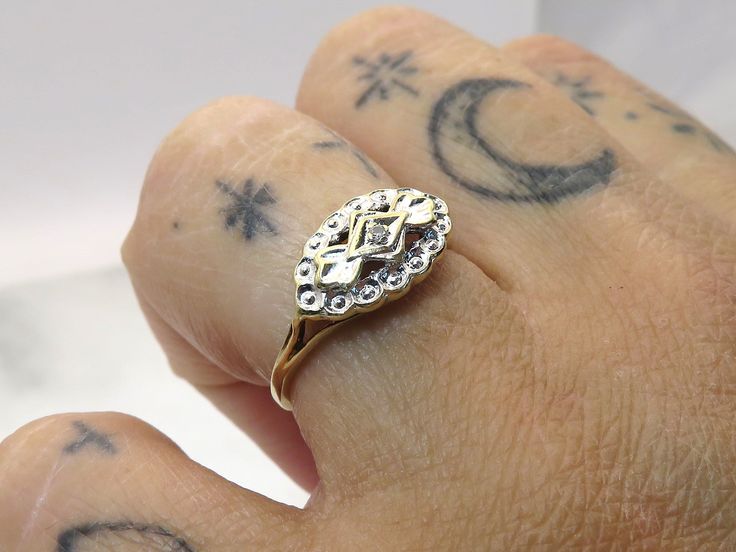 a person's hand with tattoos and a gold ring on top of their finger