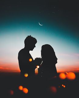 two people standing next to each other with the moon in the sky above them,