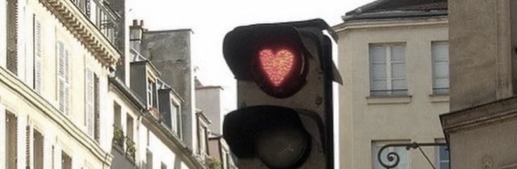 a traffic light with a heart on it in the middle of an urban area,