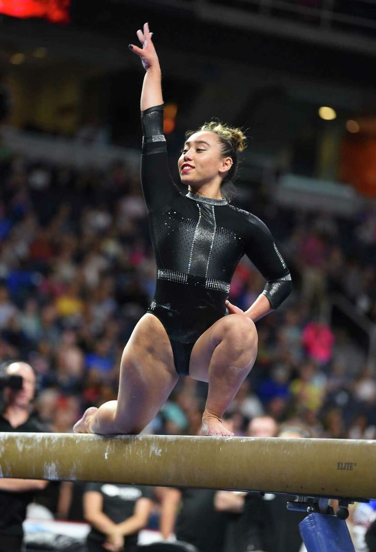 a woman is standing on a beam in the middle of a gymnastics competition while people watch