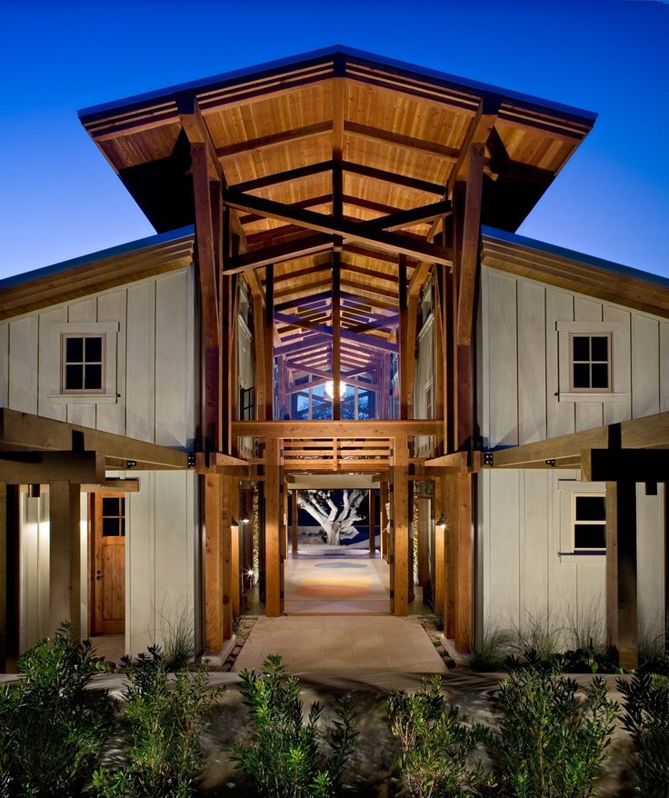 the front entrance to a large building with wooden beams and pillars on each side is lit up at night