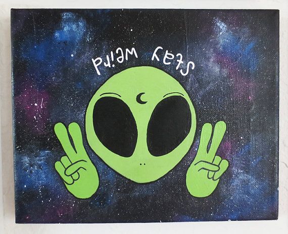 an alien painted on the side of a wall with two fingers up in front of it