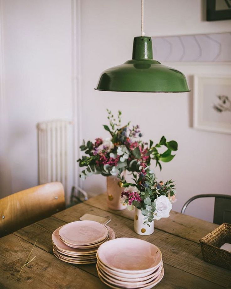 a wooden table topped with plates and vase filled with flowers