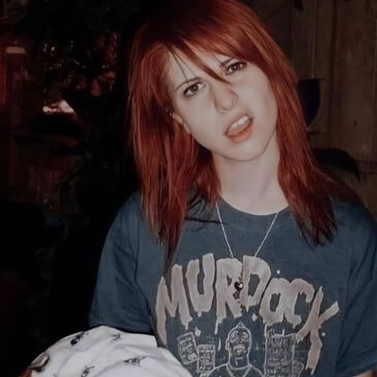 a young woman with red hair and piercings holding a white object in her hands