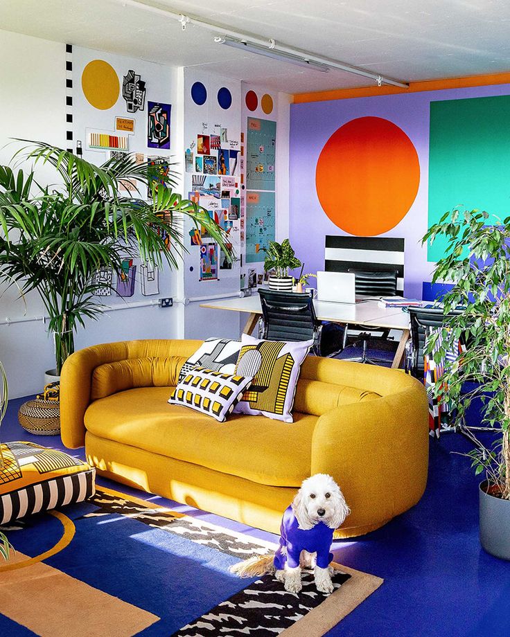 a living room filled with yellow couches and lots of colorful decor on the walls