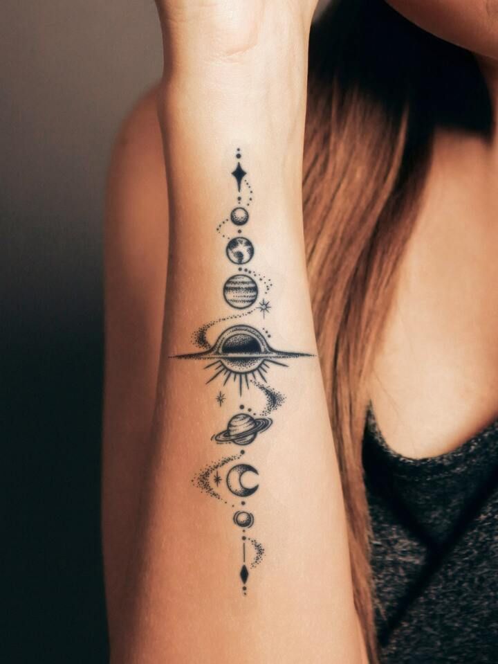 a woman's wrist tattoo with planets and stars on her left arm, in black ink