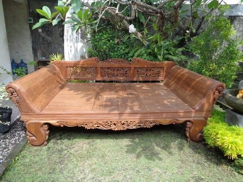 a wooden bench sitting on top of a lush green field next to a tree and shrubbery