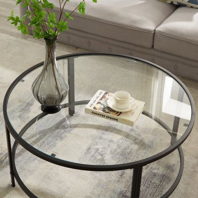 a glass table with a book and vase on it in the middle of a living room