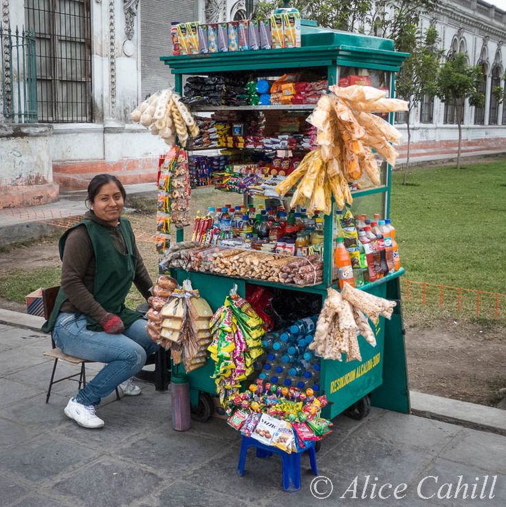 a woman sitting on a chair in front of a stand filled with food and snacks