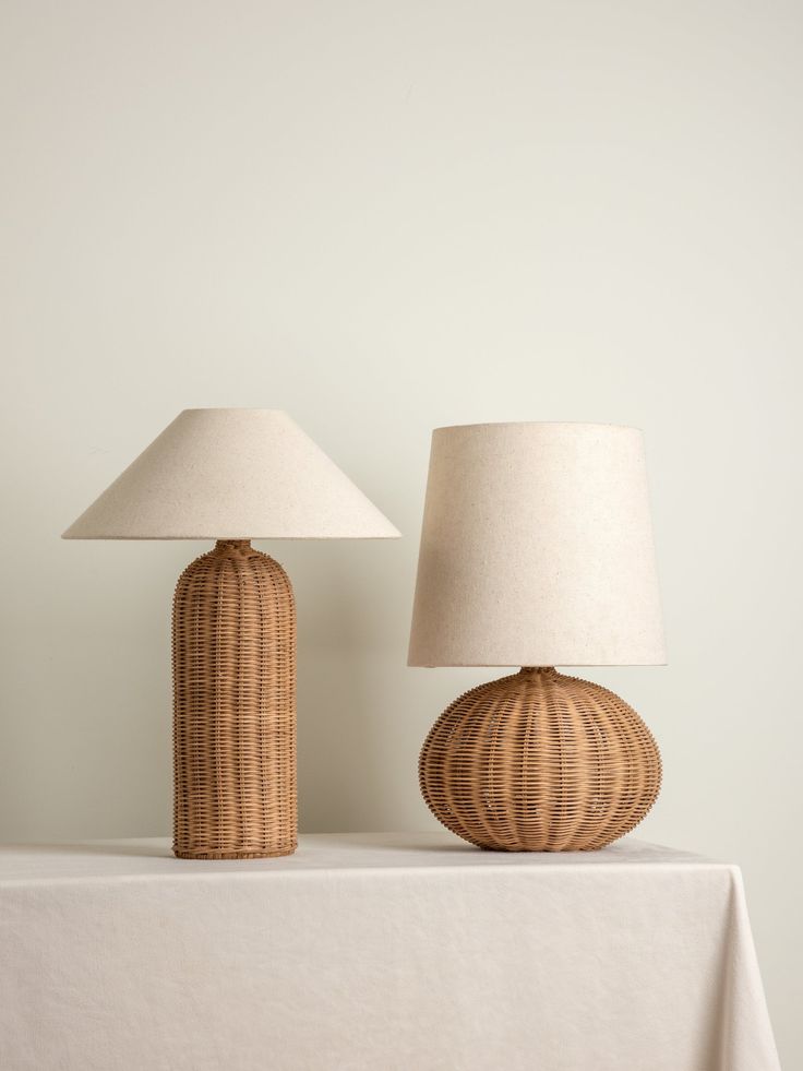 two lamps sitting on top of a table next to a white cloth covered tablecloth