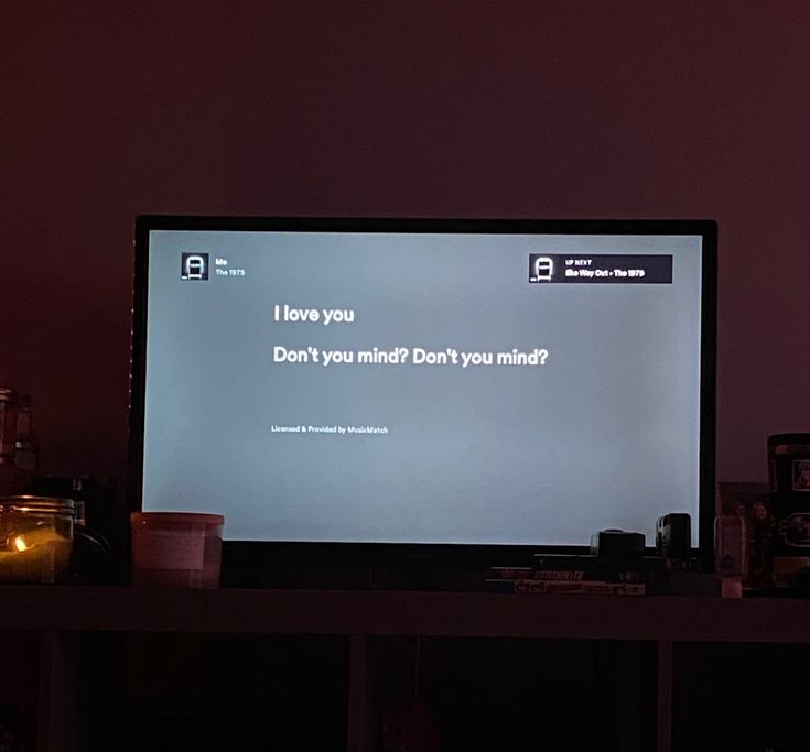 a flat screen tv sitting on top of a wooden table next to a candle lit wall