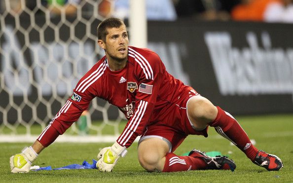 a soccer player laying on the ground with his head in his hands and holding a ball