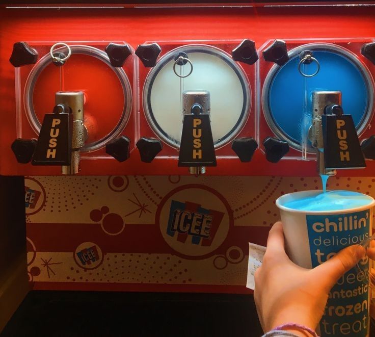 a person holding a cup in front of a vending machine that has ice cream on it