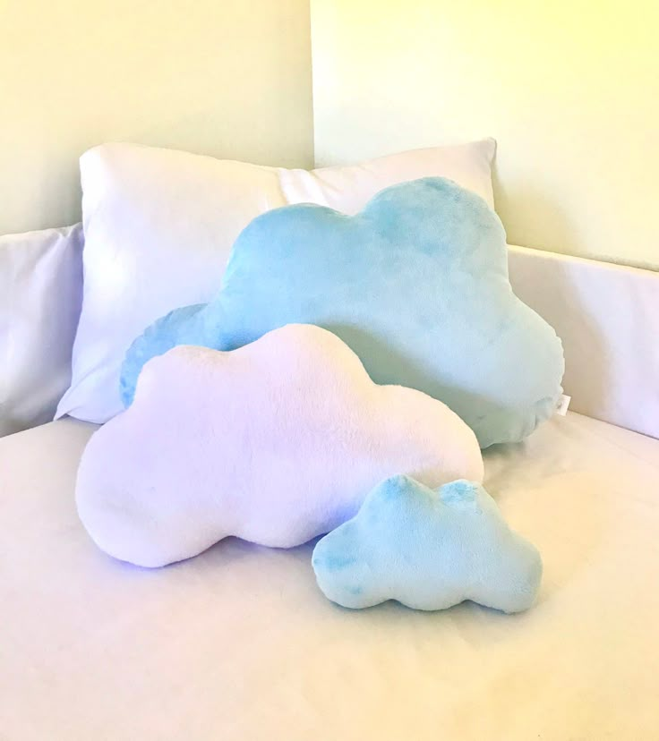 two pillows that are sitting on top of a white pillowcase, one is blue and the other is white