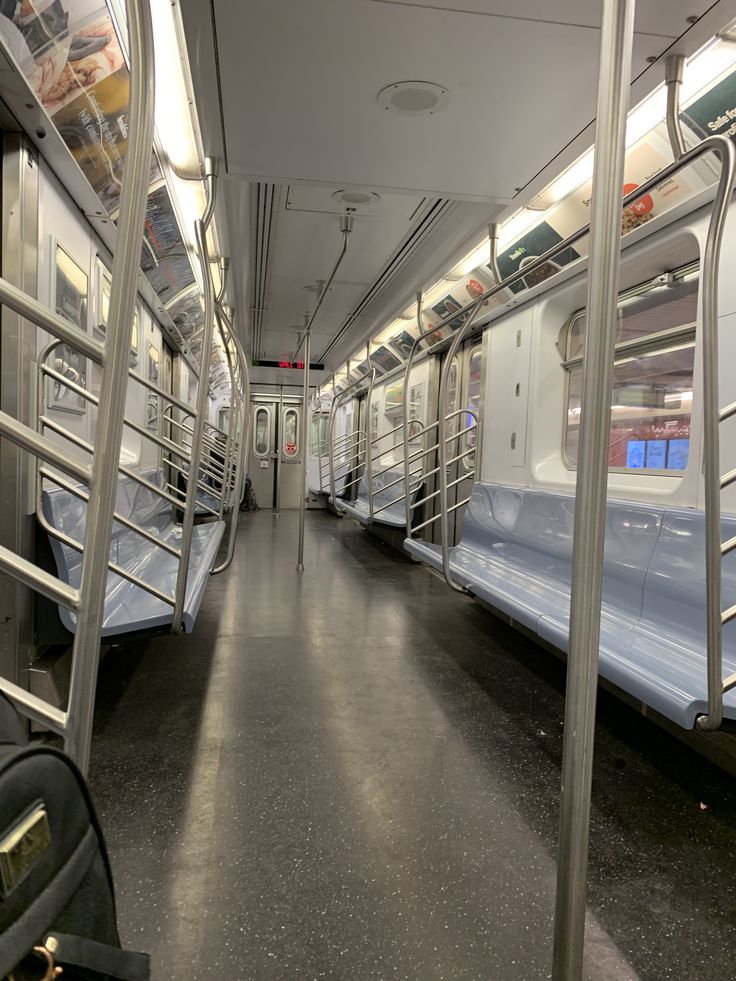 the inside of a subway car with several seats and railings on each side,