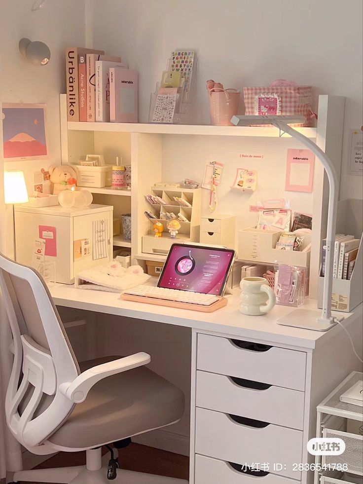 a white desk topped with a laptop computer next to a lamp and drawers in a room