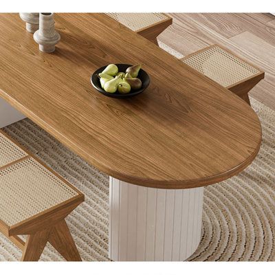 a bowl of fruit sitting on top of a wooden table next to two stools