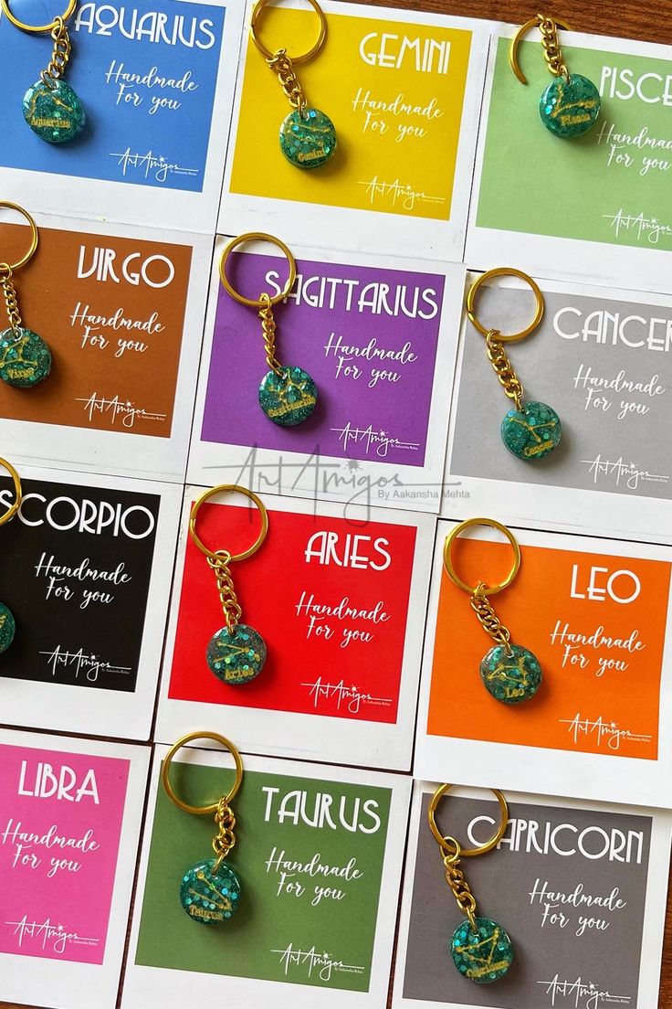 twelve zodiac signs are displayed on cards with gold chains and charms in different colors that spell out the zodiac sign