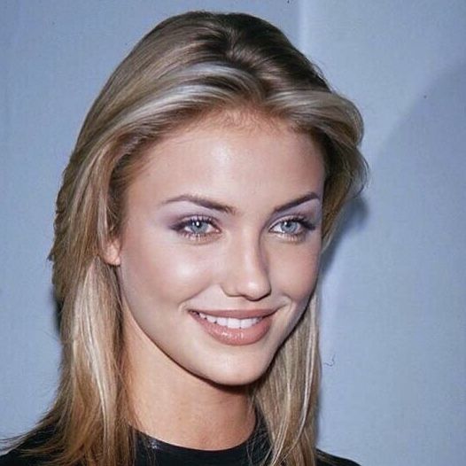 a close up of a woman with blonde hair and blue eyes smiling at the camera