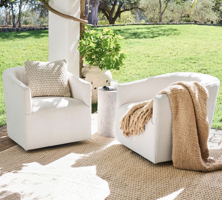 two white chairs sitting on top of a rug next to each other in front of a tree