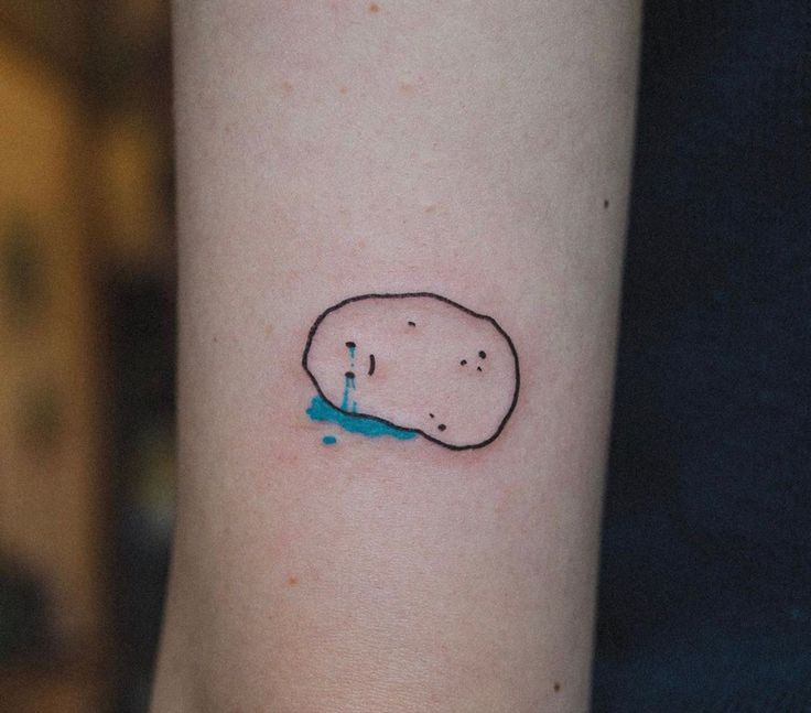 a small tattoo on the arm of a person with a blue substance in front of it