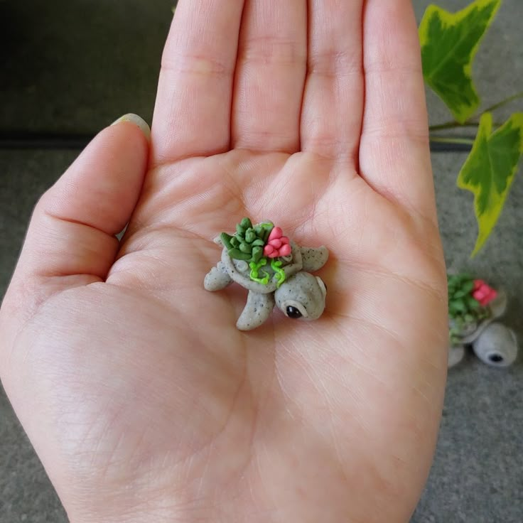 a hand holding a tiny figurine in it's palm with flowers on it