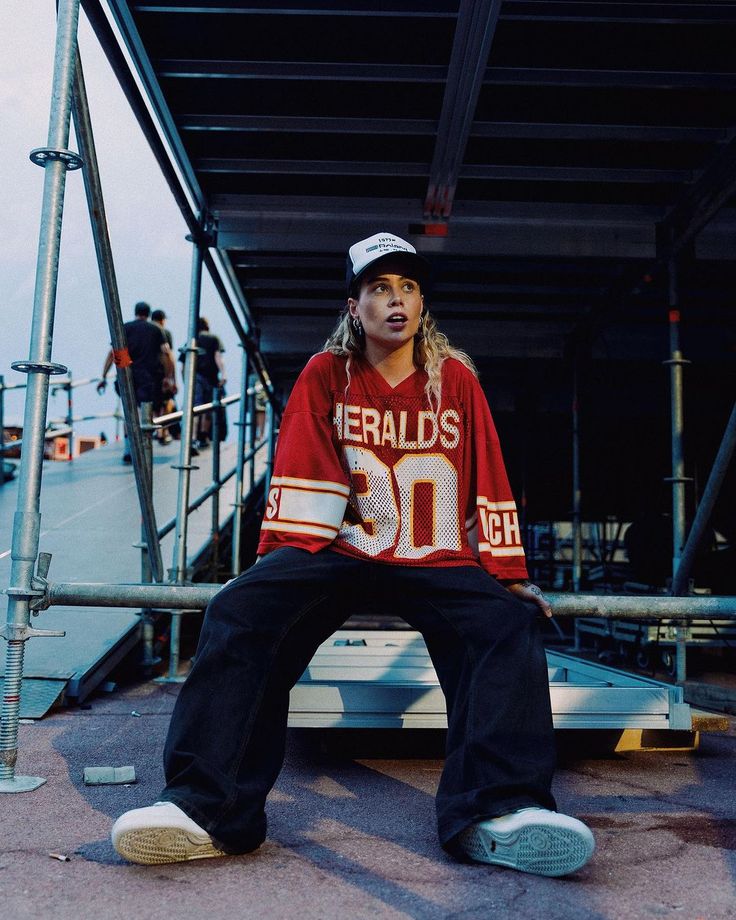 a young man sitting on top of a metal rail next to a building with people in the background