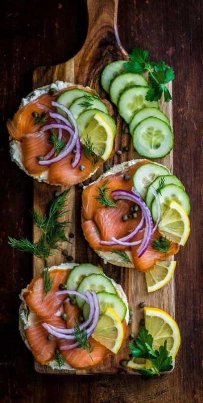 salmon and cucumber sandwiches with dill pickles on a wooden cutting board